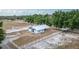 Aerial view of a horse barn with white fencing surrounding the property, complemented by mature trees at 2070 W Lake Hamilton Dr, Winter Haven, FL 33881