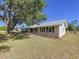 Inviting single-story home featuring black shutters, metal roof, manicured landscaping, and a large shade tree at 2171 Sophia S Pl, Lakeland, FL 33811