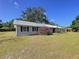 Cozy single-story home with black shutters, metal roof, front yard, and a large shade tree at 2171 Sophia S Pl, Lakeland, FL 33811