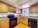 Kitchen features wooden cabinets, a black electric range and oven, and a double sink with a view from the window at 2171 Sophia S Pl, Lakeland, FL 33811