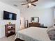 Bright main bedroom featuring tile floors, ceiling fan, mounted television, and wooden furniture at 2318 Rush Bay Way, Orlando, FL 32824