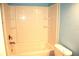 Bathroom featuring a tub with a shower and a white tiled enclosure, along with a toilet at 255 S Pennsylvania Ave, Lake Alfred, FL 33850