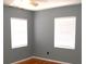 Bedroom featuring hardwood floors, gray walls and two white windows with blinds at 255 S Pennsylvania Ave, Lake Alfred, FL 33850