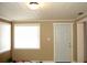 Living room featuring an exterior door, two windows with white blinds, beige walls, and crown molding at 255 S Pennsylvania Ave, Lake Alfred, FL 33850