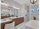 Modern bathroom with double sinks, wooden cabinets, large mirror, walk-in shower, and soaking tub at 2551 Delphi Woods Cir, Lakeland, FL 33812