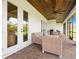 Covered outdoor patio featuring brick flooring, French doors, and comfortable wicker seating at 2551 Delphi Woods Cir, Lakeland, FL 33812