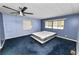 Bedroom with blue walls and carpet, ceiling fan, and multiple windows bringing in natural light at 3027 Mimosa Way, Lakeland, FL 33801