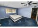 Bedroom with blue walls and carpet, ceiling fan, and view into hall and kitchen area at 3027 Mimosa Way, Lakeland, FL 33801