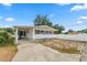 Charming single-story home with covered parking and a partially fenced yard on a sunny day at 3027 Mimosa Way, Lakeland, FL 33801