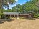 Front view of a brick home with a long driveway, manicured lawn, and mature trees providing shade at 3441 Sherertz Rd, Lakeland, FL 33810