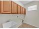 Bright laundry room with tile floors, utility sink, and wooden cabinets at 3592 Prescott Loop, Lakeland, FL 33810