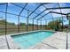 A screened-in pool area features a paved deck and clear blue water, perfect for relaxation and recreation at 3664 Frentress Dr, Lakeland, FL 33812