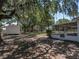 Backyard with large shade trees and home including screened lanai on right at 3705 Garland St, Mulberry, FL 33860