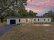 Charming single-story home with fresh exterior paint, shutters, a new roof and a paved driveway at dusk at 3705 Garland St, Mulberry, FL 33860