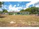 View of the backyard with a green home, sparse lawn, trees and blue skies at 400 6Th Ne St, Fort Meade, FL 33841
