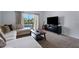 This living room features plush carpet, natural light, a comfortable couch, and a view of the pond at 4078 Winding Vine Dr, Lakeland, FL 33812