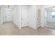 Bright hallway with neutral tile flooring, white walls, and doorways leading to various rooms in the home at 4203 San Rocco Way, Winter Haven, FL 33884