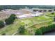 Aerial view of golf course, clubhouse and green spaces with trees and a parking lot in view at 4540 Park Ave, Indian Lake Estates, FL 33855