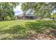 Spacious backyard with lush green grass, mature trees, landscaping and screened-in pool, offering privacy and serenity at 4540 Park Ave, Indian Lake Estates, FL 33855