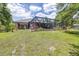 Expansive backyard featuring lush green grass, landscaping, a screened-in pool, and views of the surrounding greenery at 4540 Park Ave, Indian Lake Estates, FL 33855