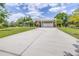 Long concrete driveway leading to a two-car garage and carport, providing ample parking at 4540 Park Ave, Indian Lake Estates, FL 33855