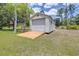 Detached garage with a roll-up door and a wooden ramp on a grass yard, perfect for storage at 4540 Park Ave, Indian Lake Estates, FL 33855
