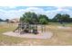 Outdoor playground with slides and climbing features, surrounded by a grassy area and mature trees at 4540 Park Ave, Indian Lake Estates, FL 33855