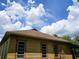 Exterior view of a house showing a brown roof and light yellow siding under a cloudy blue sky at 4885 Cherry Dr, Mulberry, FL 33860