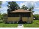 A charming home exterior showing a screened front porch under a sunny, partly cloudy sky at 4885 Cherry Dr, Mulberry, FL 33860