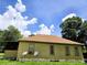 Side exterior view of the house featuring satellite dishes, jalousie windows and yellow siding at 4885 Cherry Dr, Mulberry, FL 33860