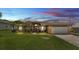 Charming single-story home featuring a well-manicured lawn, attached garage, and inviting curb appeal at sunset at 4965 Tradition Dr, Lakeland, FL 33812