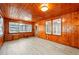 Spacious living room featuring wood paneled walls, three windows, and vinyl floors at 522 Channing Rd, Lakeland, FL 33805