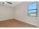 Bright bedroom with hardwood floors, a ceiling fan, and a window overlooking the neighborhood at 5390 Clubhouse Hills Ln, Lakeland, FL 33812