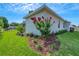 Beautiful landscaping showcasing a vibrant red flowering tree, lush green lawn, and well-kept garden beds at 5390 Clubhouse Hills Ln, Lakeland, FL 33812