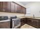 Well-equipped laundry room featuring dark cabinetry, granite countertops, stainless steel washer and dryer, and tile floors at 6347 Ashley Dr, Lakeland, FL 33813