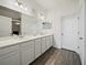 Bright bathroom featuring double sinks with white cabinets, wood-look flooring, and a glass-enclosed shower at 6520 Great Bear Dr, Lakeland, FL 33805