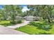 Aerial view of a single-story home with a long driveway, a well-maintained yard, and mature trees at 6735 Forestwood W Dr, Lakeland, FL 33811
