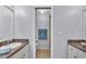 Bright bathroom featuring dual sinks, granite counters, and a tiled shower stall at 6735 Forestwood W Dr, Lakeland, FL 33811