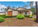 Single-story home exterior with lush trimmed hedges, a front door with pillars, and a two-car attached garage at 7952 Grand Pines Blvd, Lakeland, FL 33810