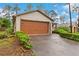 Exterior view of attached garage and driveway featuring manicured landscaping at 7952 Grand Pines Blvd, Lakeland, FL 33810