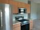 Modern kitchen featuring stainless steel appliances, light wood cabinets, and countertop with marble look at 7952 Grand Pines Blvd, Lakeland, FL 33810