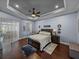 Comfortable main bedroom with tray ceiling, ceiling fan, and hardwood floors at 800 Osprey Landing Dr, Lakeland, FL 33813