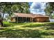Green backyard with shade trees, a screened porch, and a brick house facade at 909 Lake Deeson Pt, Lakeland, FL 33805