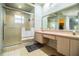 Bathroom with large mirror, double sinks, walk-in shower, tiled floors, and a window at 909 Lake Deeson Pt, Lakeland, FL 33805