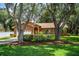 Brick home with well-maintained lawn and landscaping, framed by mature trees at 909 Lake Deeson Pt, Lakeland, FL 33805