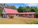 Home with brick facade, red metal roof, a two-car garage, and well-manicured lawn at 3822 Charter Rd, Lakeland, FL 33810