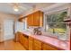 Classic kitchen with wooden cabinets, pink countertops, vintage appliances, and garden view at 3822 Charter Rd, Lakeland, FL 33810