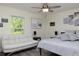 Bright bedroom with a white daybed, large window and a bed with grey comforter and lamps at 10470 Sw 139Th Ct, Dunnellon, FL 34432