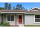 A welcoming front porch with a red front door, a new storm door, and decorative plants at 10470 Sw 139Th Ct, Dunnellon, FL 34432