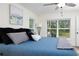 Bright main bedroom featuring wood-look floors, a modern ceiling fan, and large windows showcasing lush greenery at 10470 Sw 139Th Ct, Dunnellon, FL 34432